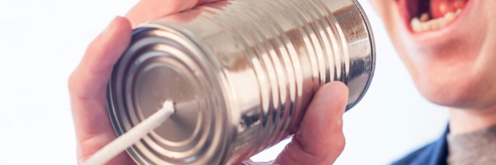 Image shows a woman talking into a metal can with a string attached and is representative of communication, or in this specific instance, communicating your Unique Selling Proposition to the market.