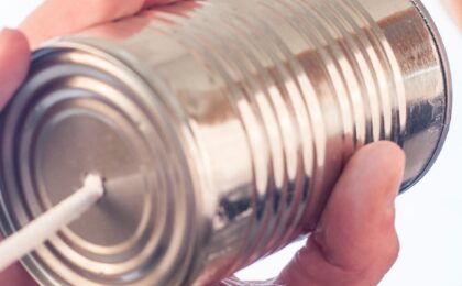 Image shows a woman talking into a metal can with a string attached and is representative of communication, or in this specific instance, communicating your Unique Selling Proposition to the market.